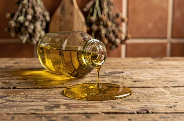 Bouteille d'huile d'olive renversée sur une table en bois rustique, symbolisant la superstition populaire de renverser de l'huile